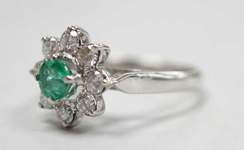 A modern 18k white metal, emerald and diamond set flower head cluster ring, size N, gross weight 4.5 grams.